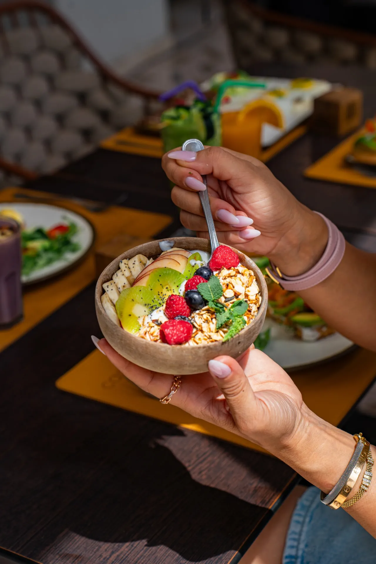 A bowl of granola with fresh fruit held above a brunch table