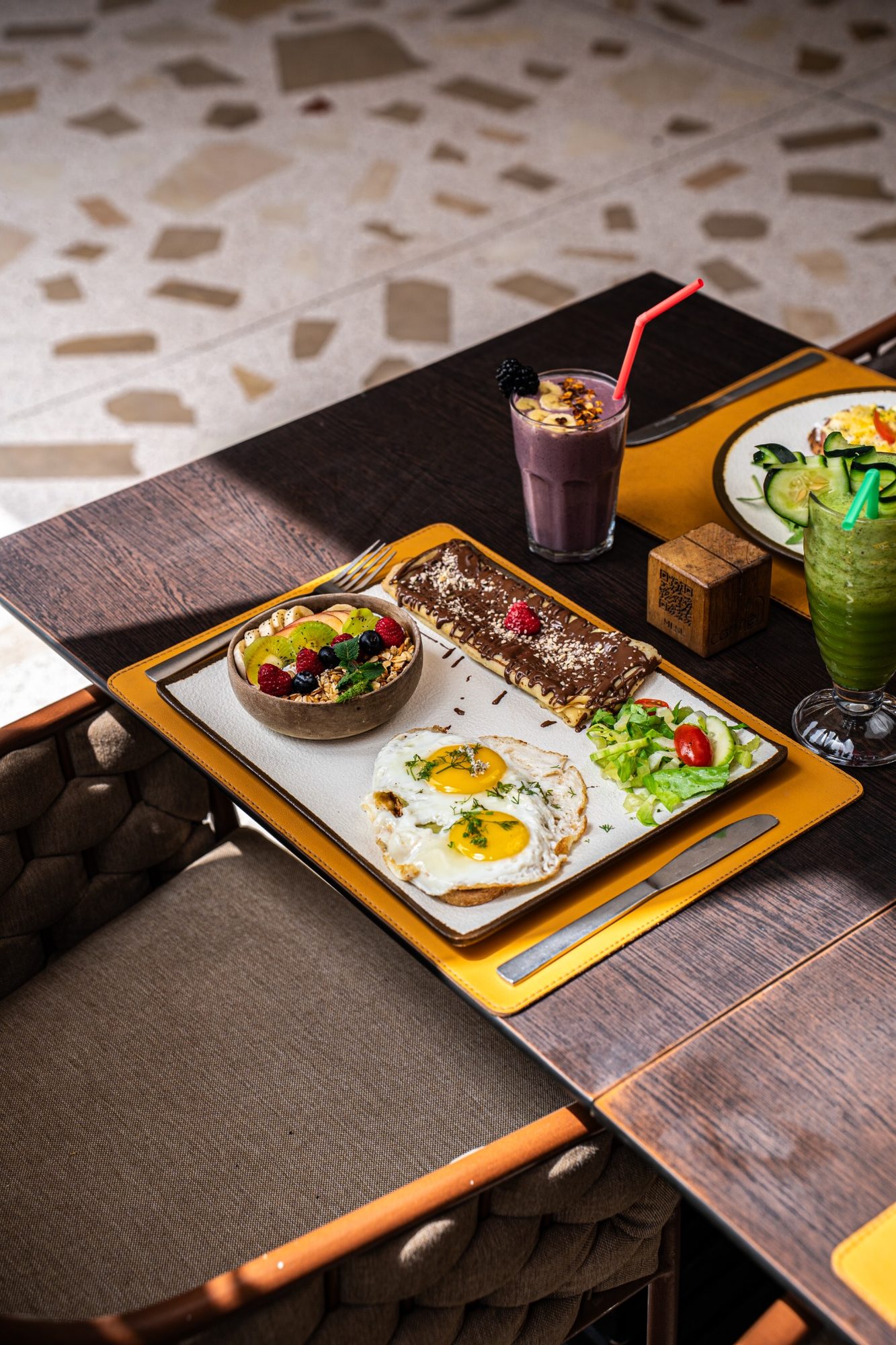 Une table de brunch garnie d'œufs, salade, granola et boissons fraîches