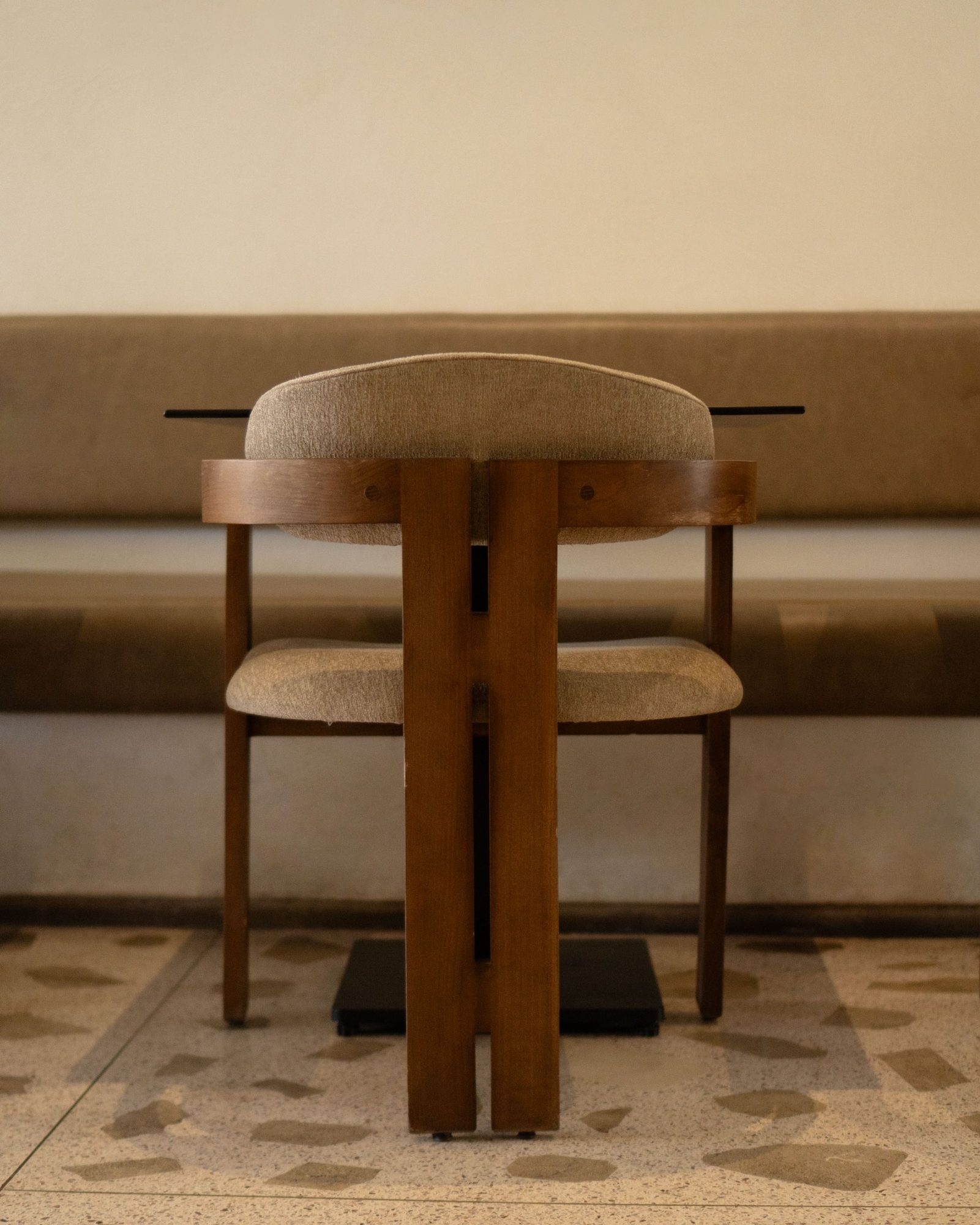 Chaise en bois arrondie contre une banquette en lin chez Carmel Marrakech