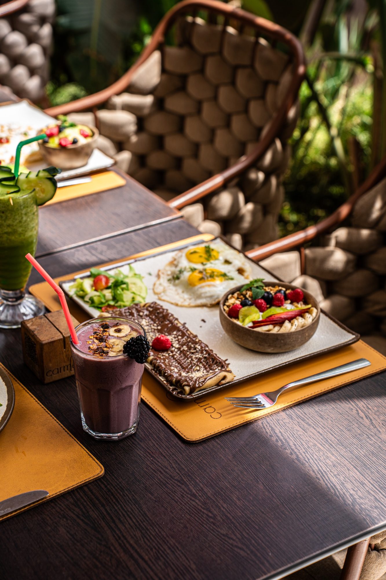 Smoothies et jus à côté d'un plateau de brunch sur la terrasse de Carmel